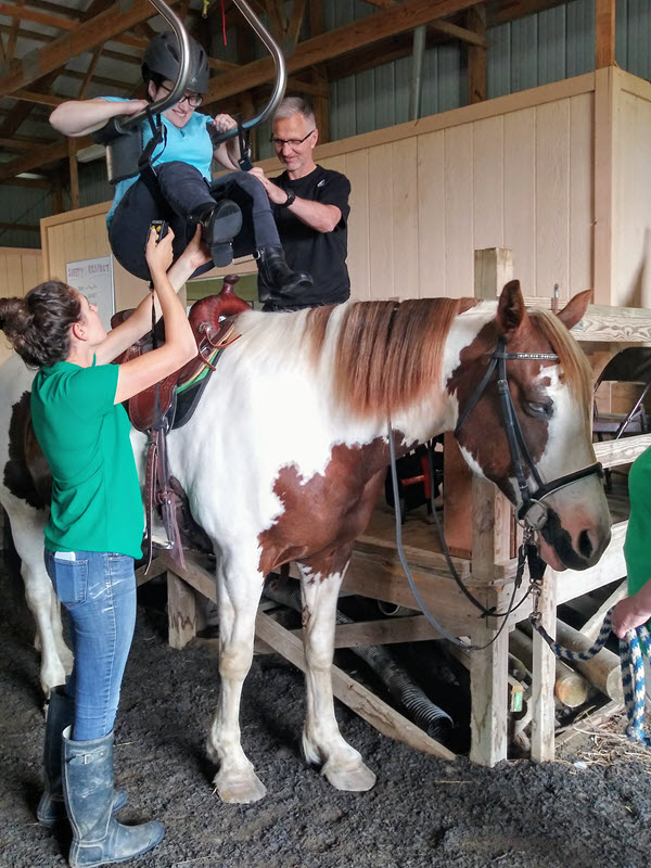 Image of individual getting onto horse at our farm